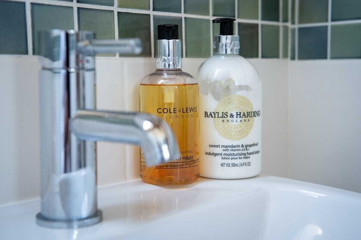 Un lavamanos de baño con dos botellas de loción para manos y un grifo moderno.