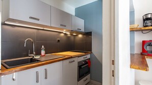 Een kleine keuken met een ingebouwde oven, een spoelbak met kraan en een aanrecht.