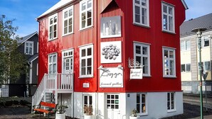 Un bâtiment rouge avec des ornements blancs, un escalier et des plantes en pot.