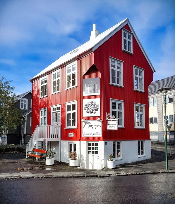 A red building with white trim, a staircase, and potted plants. - House of the Snowbird (Reykjavik)
