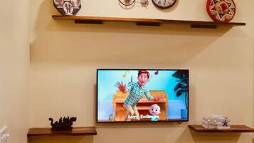 Relax in this cozy living room with a flat-screen TV and decorative items above and below.