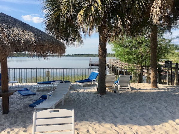 A beach area with lounge chairs and a thatched roof structure.