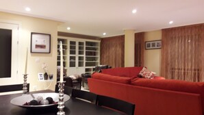 A modern living room with a red sofa, a dining table with a decorative centerpiece, and a shoe rack in the background. - DUPLEX PENTHOUSE APARTMENT in Isla Cristina. (Isla Cristina)