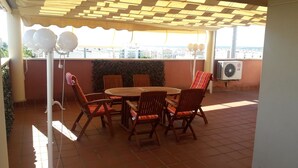 An outdoor patio with a round wooden table and four wooden chairs, a pergola overhead, and a view of the cityscape. - DUPLEX PENTHOUSE APARTMENT in Isla Cristina. (Isla Cristina)