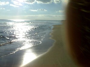 Ein Strand mit sandigem Ufer und sanften Wellen.