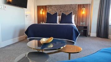 A hotel room with a bed, a round table with a bowl, and a TV on the wall.