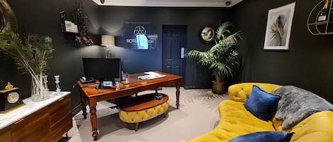 Una sala de estar moderna con un escritorio de madera, un sofá amarillo y una planta en maceta.