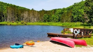 Eine Uferlandschaft mit Steg, Kajaks und Rettungsboje.
