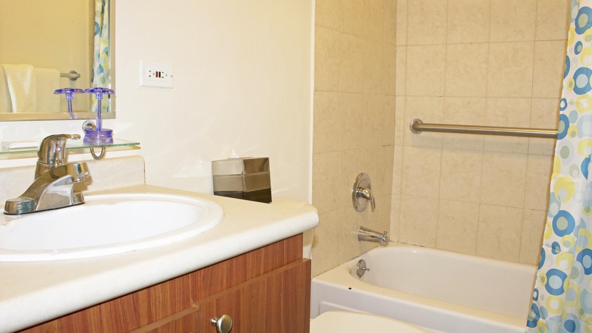 A bathroom with a sink, mirror, and bathtub.