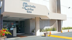Exterior do hotel Marbella del Caribe Este com fachada moderna, balcão de recepção e plantas em vasos.