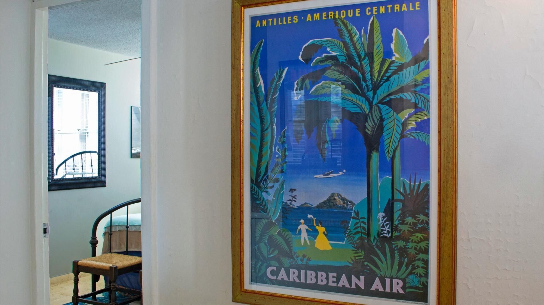 Un cartell de viatge emmarcat del Carib, amb un home i una dona a la platja, palmeres i un vaixell.