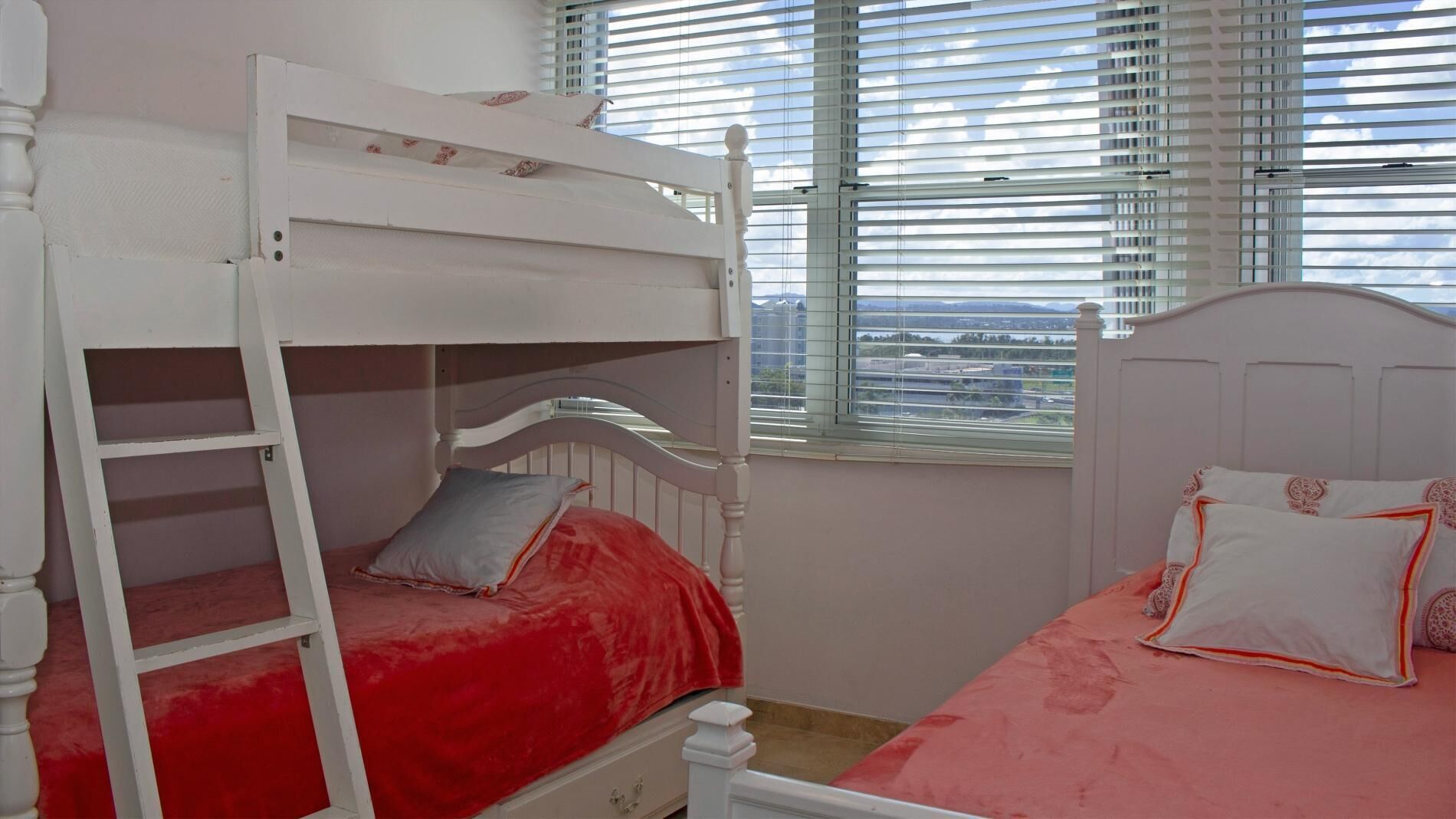 A bunk bed room with a city view through the window.