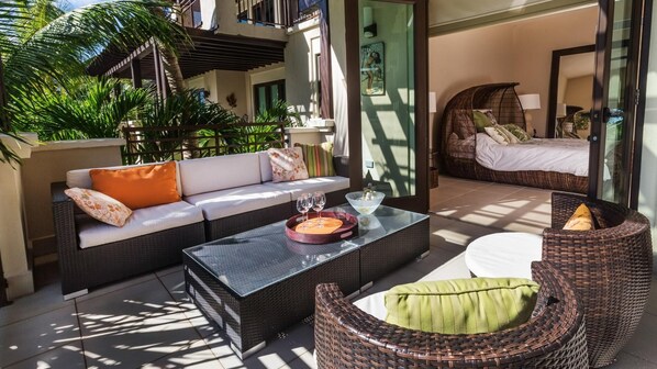A sunlit outdoor seating area with a sofa, a coffee table, and wicker chairs. - Villa Esmeralda (Río Grande)