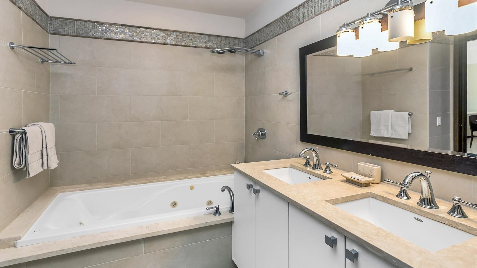 Une salle de bain moderne avec une baignoire, deux lavabos, un grand miroir et un espace douche.