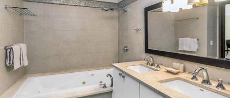 Une salle de bain moderne avec une baignoire, deux lavabos, un grand miroir et un espace douche.