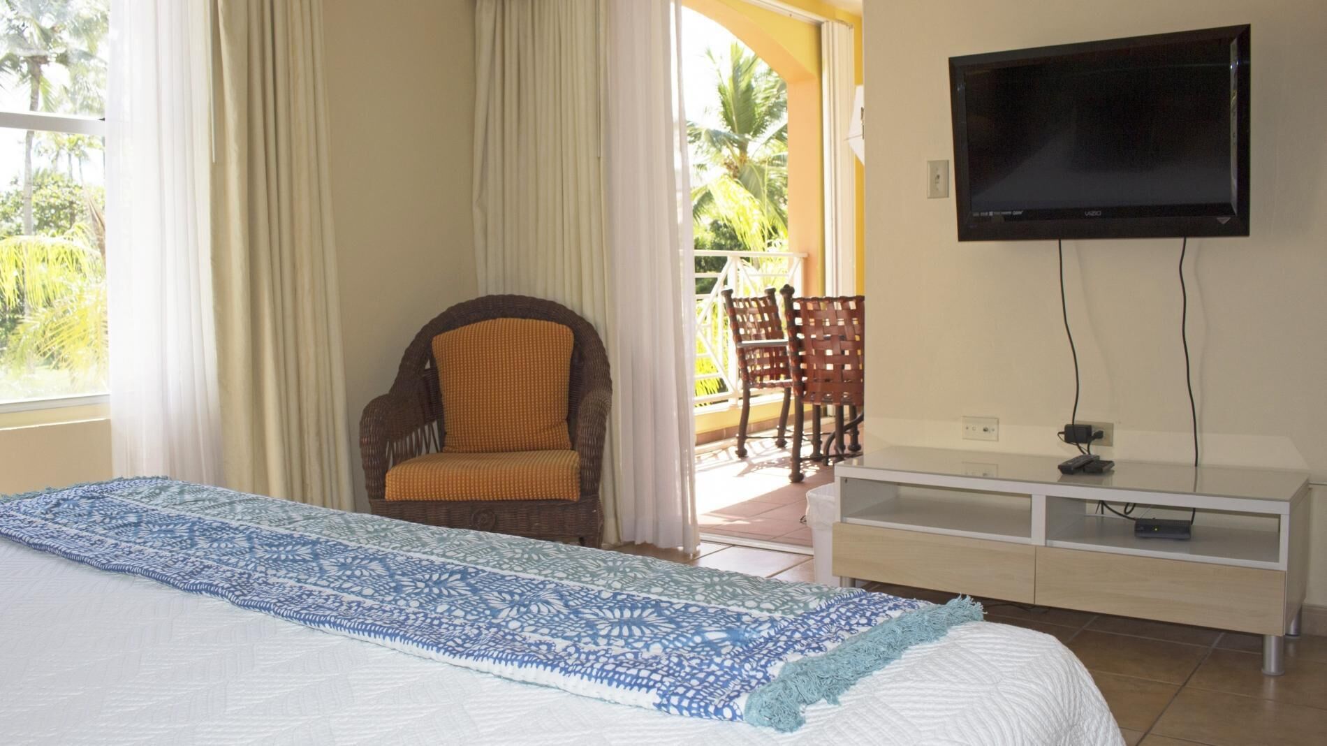 A hotel room with a large bed, a television mounted on the wall, and a view of the outdoors through a window.