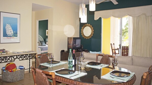 A dining area with a round table set for four, a television, and a view of the outdoors.