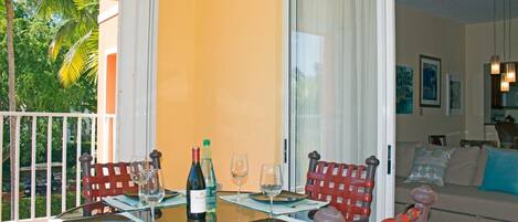Un comedor con una mesa preparada para cuatro personas, una botella de vino y dos copas de vino vacías.