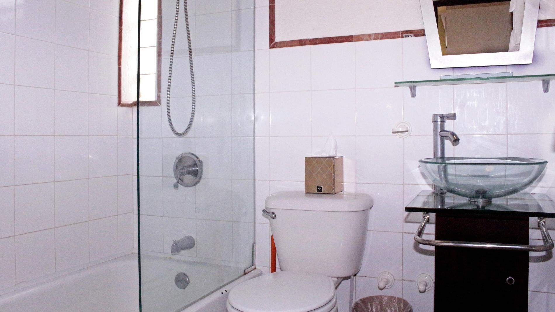 Une salle de bain dotée d’une douche à parois de verre, de toilettes et d’un lavabo en verre au design moderne.