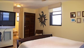 Comfortable sleeping area with a large bed, television, and window offering a view of the outside.