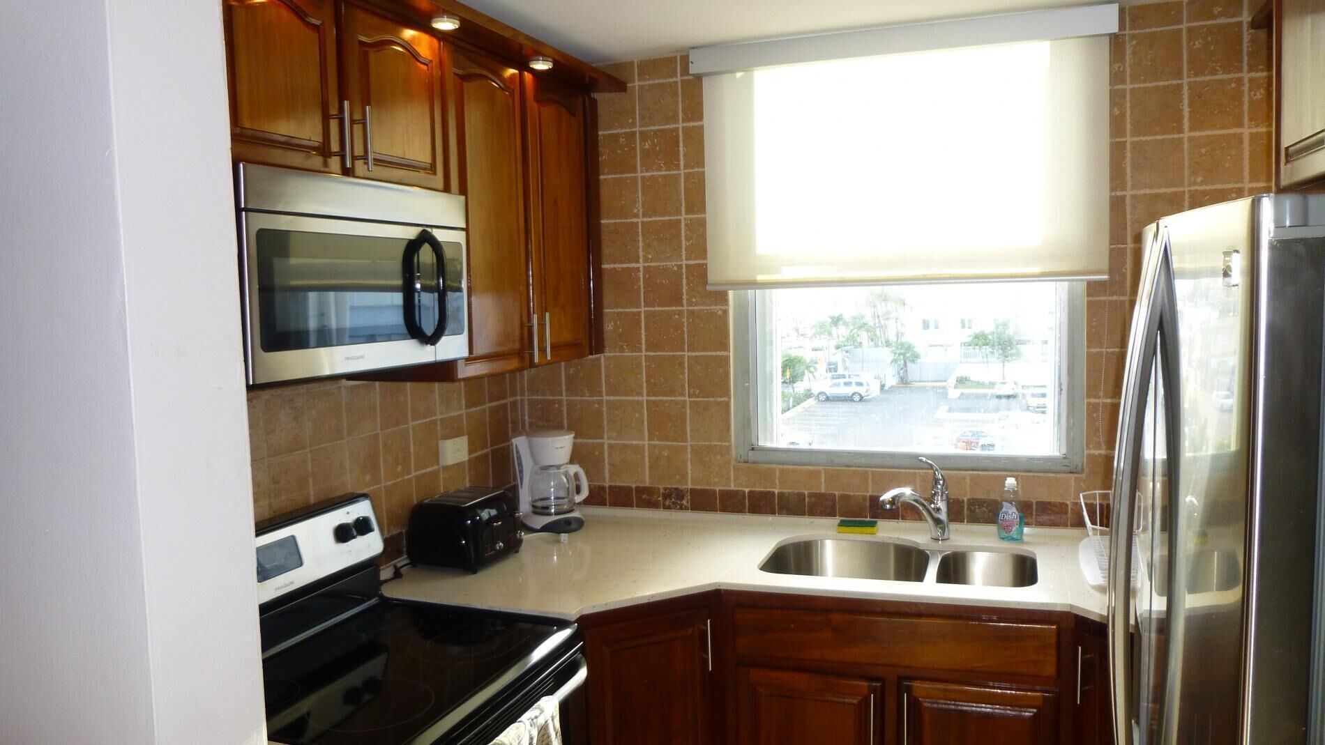 A compact kitchen with a microwave, toaster, stove, sink, and refrigerator.