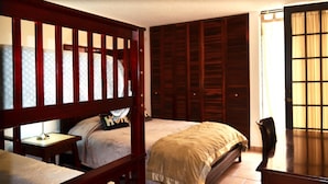 A bedroom with two beds, a wooden headboard, a bedside table, a chair, and a wardrobe. - Casa Almendro (San Juan)