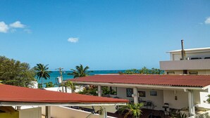 A coastal building with a red roof, white walls, and a view of the ocean. - Casa Almendro (San Juan)