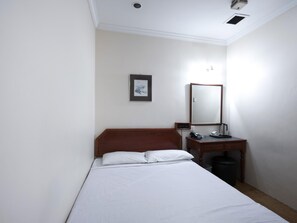 Une chambre d’hôtel avec un lit, une table de chevet avec une lampe, un miroir et un tableau encadré au mur.