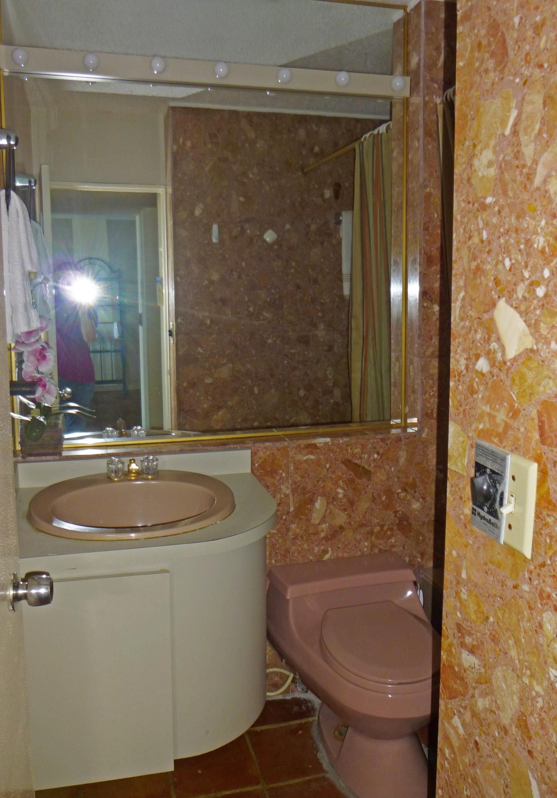 Een badkamer met een marmeren wand, een wastafel en een toilet.