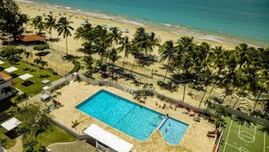 A beachside hotel with a swimming pool, palm trees, and a view of the ocean. - El Capitan (Carolina)