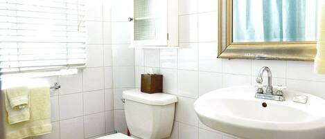 A bathroom with a toilet, sink, and window with blinds.