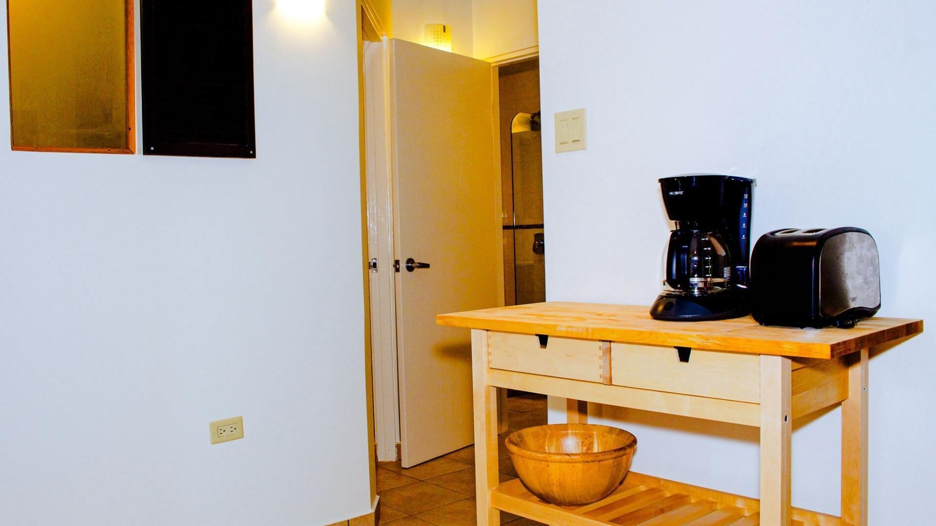 A small kitchenette with a coffee maker, toaster, and wooden table.