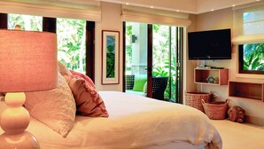A bedroom with a bed, a television, and a view of greenery outside. - Villa Margarita (Río Grande)