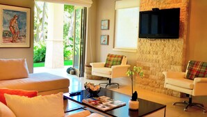 A modern living room with a sofa, armchairs, a coffee table, and a TV mounted on a stone wall. - Villa Margarita (Río Grande)