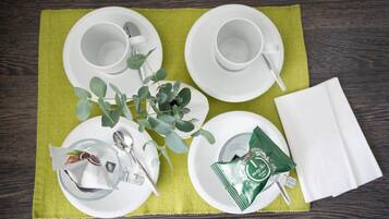 A table set with white plates, cups, a glass, a napkin, and a packet of tea.