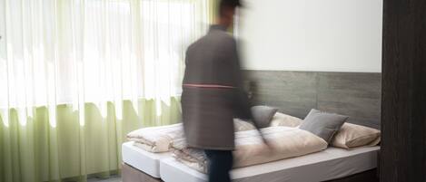 Un dormitorio moderno con una cama grande, cabecera de madera y cortinas translúcidas.