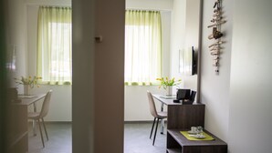 A dining area with a table, chairs, and a small side table with a cup and saucer. - eee hotel Liezen (Liezen)