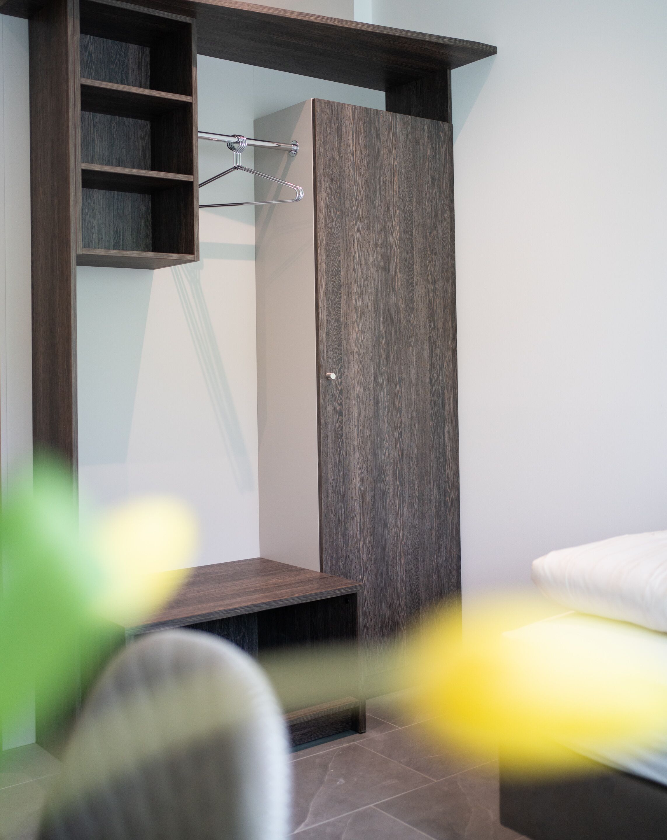 Una camera da letto moderna con armadio a muro, una panca e una rastrelliera appendiabiti.