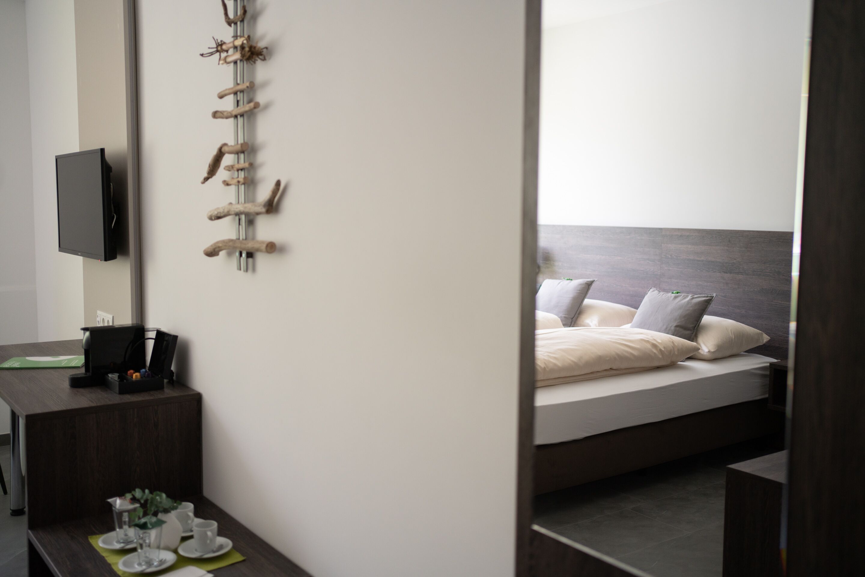 Une chambre d’hôtel moderne équipée d’un lit, d’un bureau avec un téléviseur à écran plat et d’un porte-manteau fixé au mur.
