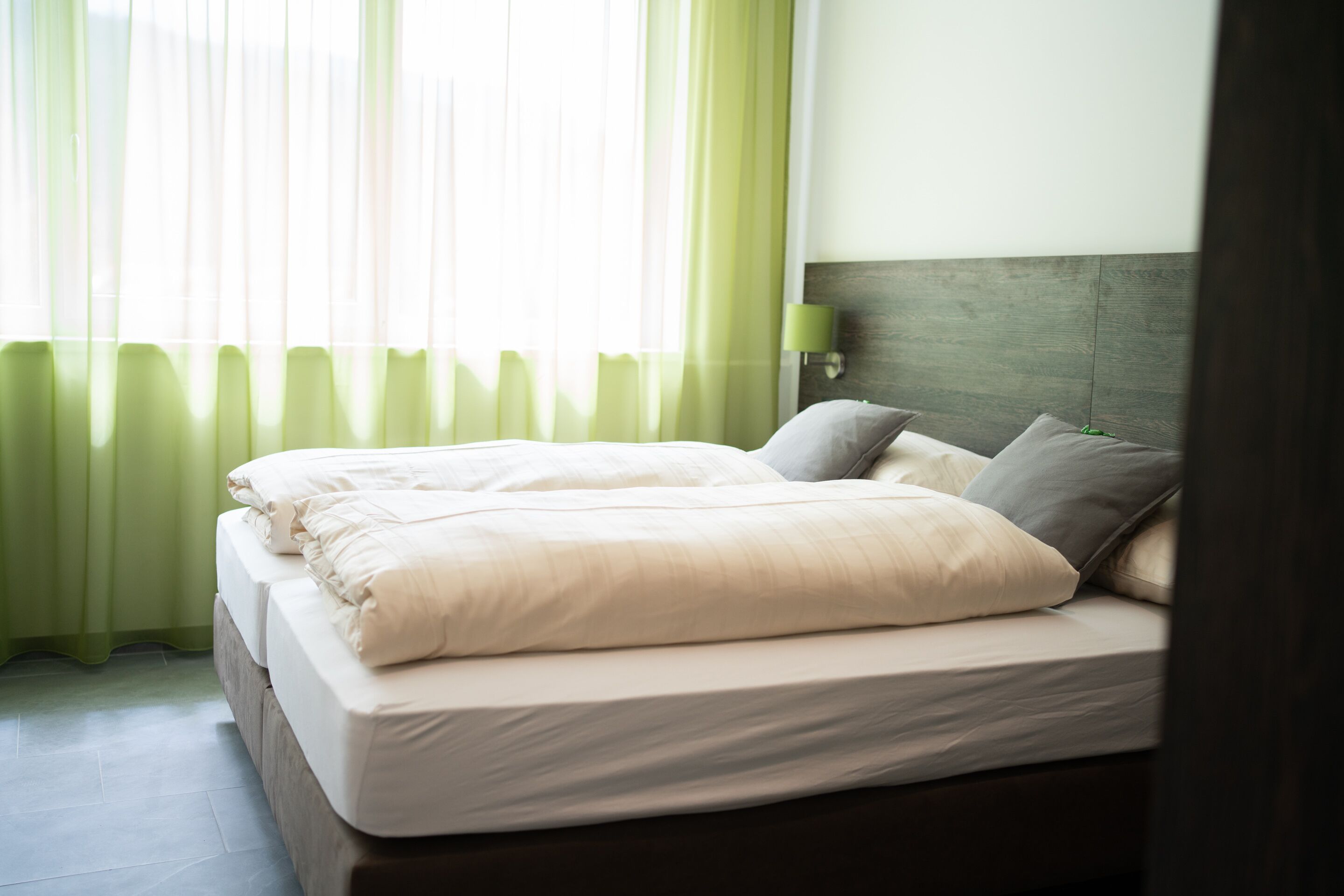 A neatly made double bed with white linens and a wooden headboard.