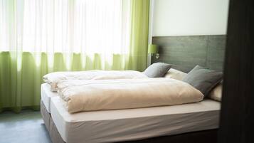 A neatly made double bed with white linens and a wooden headboard.