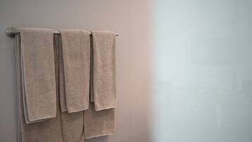A bathroom with three beige towels hanging on a metal towel rack.