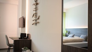A modern hotel room with a desk, chair, and a bed with a headboard. - eee hotel Liezen (Liezen)