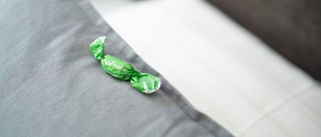 Un almohadón con una etiqueta verde de hotel sobre un sofá gris y blanco.