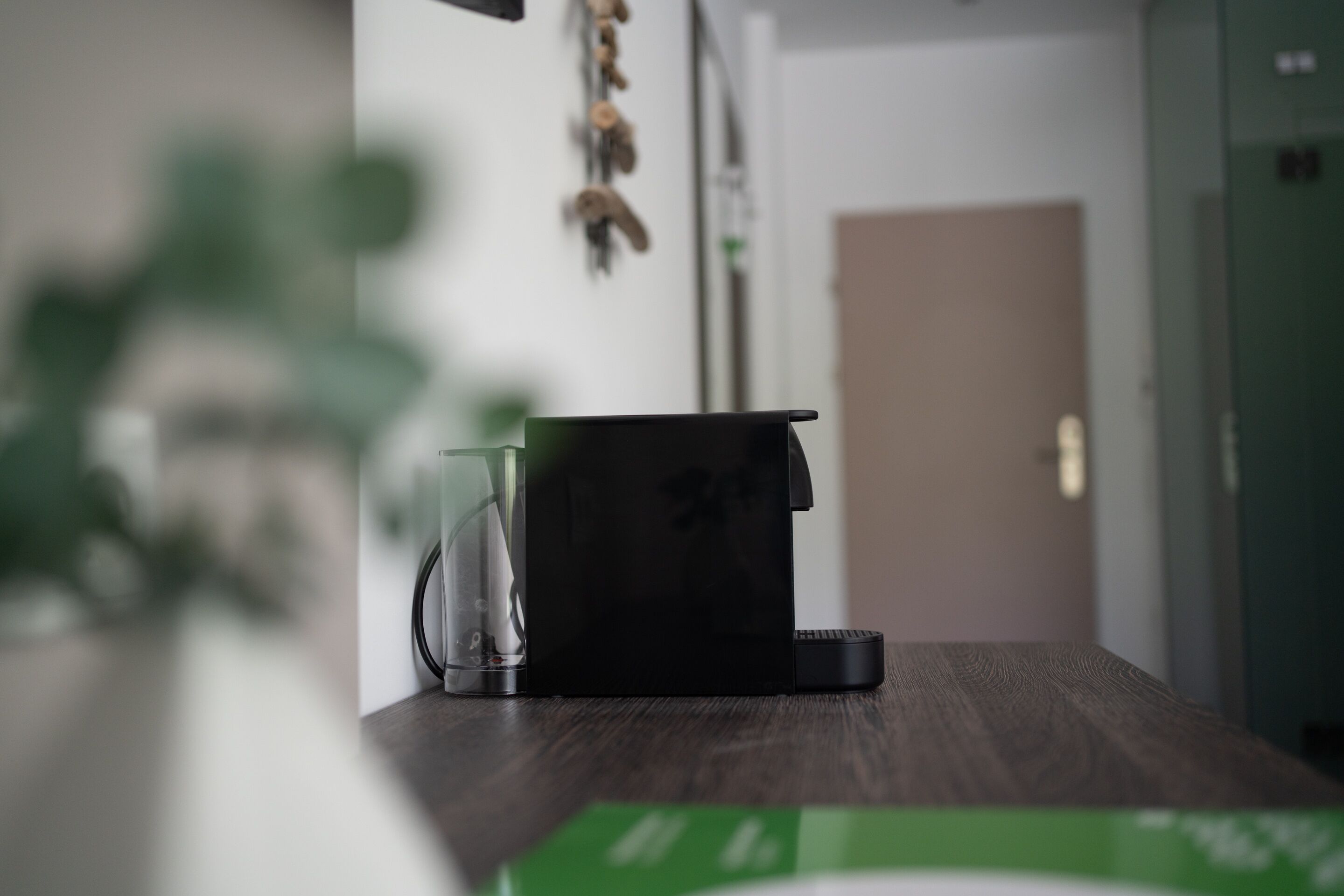 Una cocina con cafetera, un recipiente de vidrio y una caja verde sobre la encimera.
