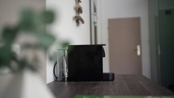 Una cocina con cafetera, un recipiente de vidrio y una caja verde sobre la encimera.