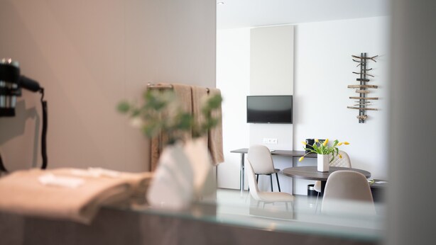 A modern dining area with a glass table, chairs, and a vase with flowers. - eee hotel Liezen (Liezen)