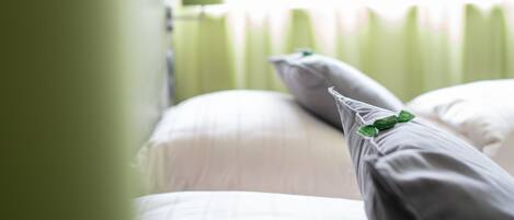 Uma cama com lençóis brancos e um travesseiro decorado com uma folha verde.