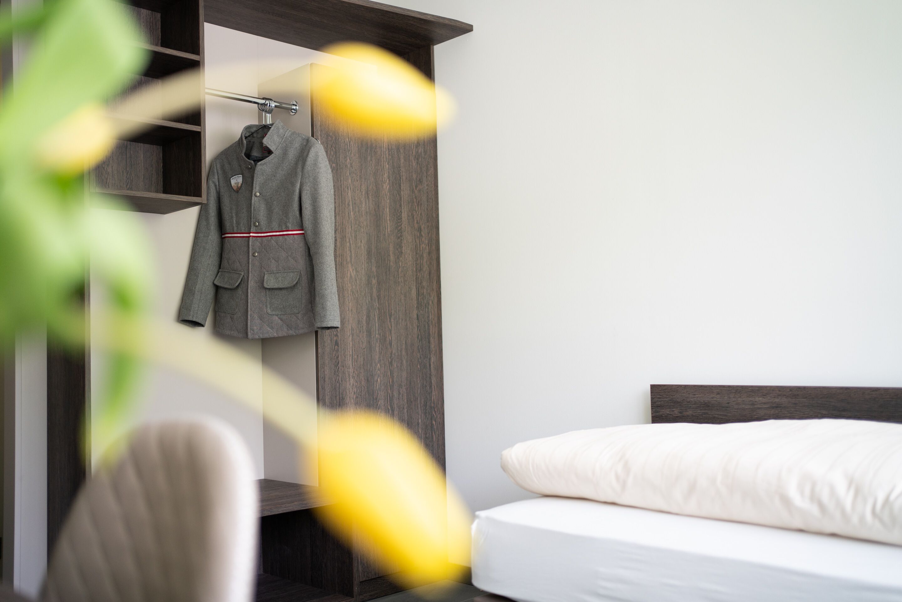 Een moderne slaapkamer met een bed, een kapstok en een houten garderobe.