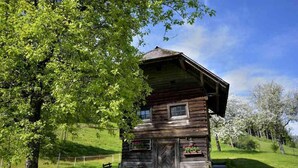 A rustic wooden cabin with a hipped roof, a front porch with a bench, and a small window. - Tameggerhof (Gurk)